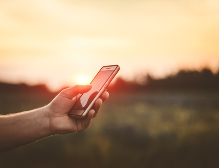 Mobile in hand at sunset. Game on the phone.の写真素材