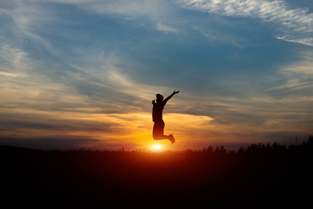 Silhouette of a cheerful man at sunset. Leap at sunset.の写真素材