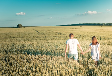 Fall in love with the field. The guy and the girl are holding hands at the talk of the sun.の写真素材