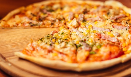 Hot pizza slice with melting cheese on a rustic wooden table.の写真素材