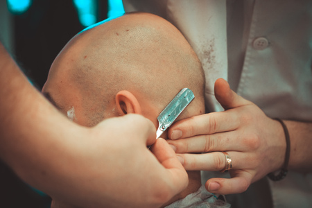 The man is shaving everything apart from the mustache. Shaving a head in a barbershop.の写真素材