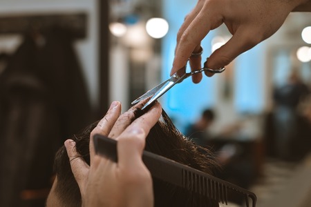 Closeup of smiling man getting an haircut from barberの写真素材