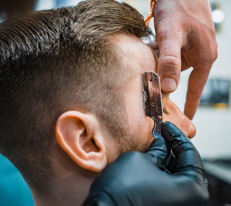 Ideal shape of the beards and haircuts in barbershop. Barber suggests the outline with a razor. Men's body care. Soft focus.の写真素材