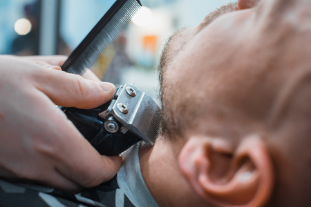 Barber leveled his beard to the client machine for shaving. The client gets the perfect shape of your beard. Soft focus.の写真素材