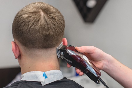 men's hairstyling and haircutting with hair clipper in a barber shop or hair salonの写真素材