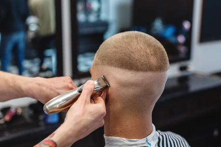 men's hairstyling and haircutting with hair clipper in a barber shop or hair salonの写真素材