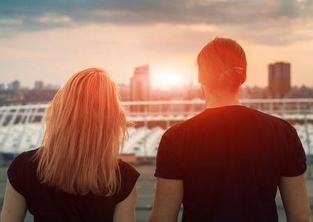Two lovers embracing overlooking the city at sunrise sunset. Romantic setting.