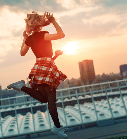 Silhouette of happy joyful woman jumping and having fun in the city against the sunset. Freedom and leisure vacation concept.の写真素材