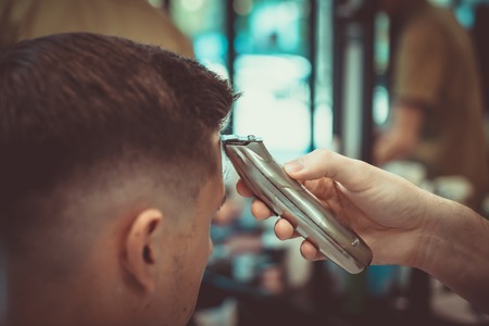 Confident guy sitting at beauty salon . Man haircut. Soft focus.