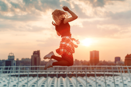 Happy woman jumping against beautiful sunset. Freedom, enjoyment concept.の写真素材