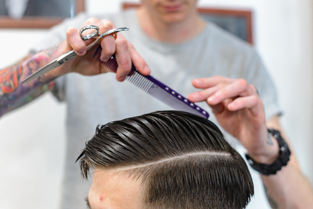 Men's hair care. Haircut in barbershop. Barber makes a beautiful hairstyle for the client.の写真素材