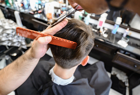 Professional barber styling hair of his client. Selective focus.の写真素材