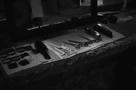 The tools of a Barber on the desktop in front of the mirror .Black and white photo of hairdresser tools. Photo in dark key.の写真素材