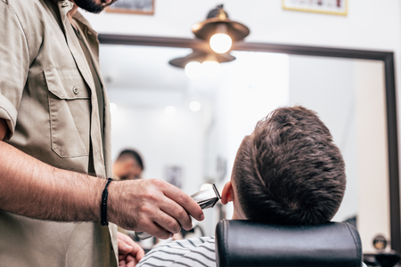 Shave beards in barbercos. Men's haircut and facial care. Barber makes a haircut to the client.の写真素材