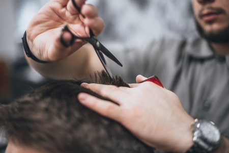 Hair Care. Barber makes a haircut with scissors. Soft focus.の写真素材