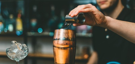 A barman pours alcohol into a shaker for a cocktail. Great plan.の写真素材