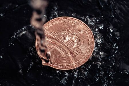 Bitcoin on black background. Bitcoin laundering with water. Economic crisis.の写真素材