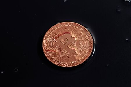 Bitcoin on black background. Bitcoin laundering with water. Economic crisis.の写真素材