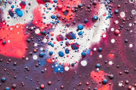Color drops floating in oil and water over a colorful underground with oil painting effect.の写真素材