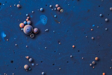 Color drops floating in oil and water over a colorful underground with oil painting effect.の写真素材