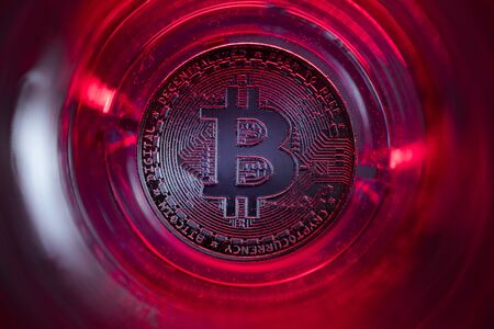 Bitcoin at the bottom of the glass with water and red lights.の写真素材