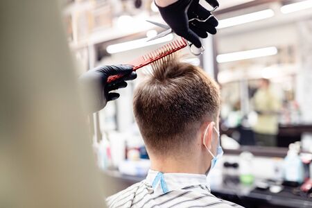 Mens haircut in a barbershop. Client and barber in anti-virus masks.の写真素材