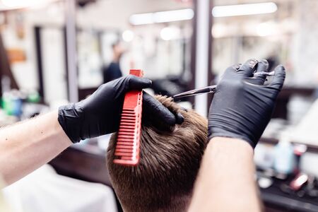 Mens haircut in a barbershop. Client and barber in anti-virus masks.の写真素材