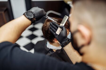 Barber makes a haircut and hair styling in a barbershop, beauty salon.の写真素材