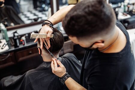 Barber makes a haircut and hair styling in a barbershop, beauty salon.の写真素材