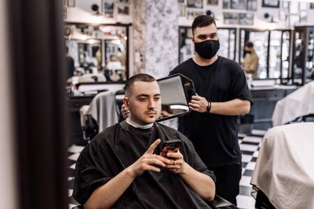 The final work of the barber. The client looks at the haircut through the mirror.の写真素材