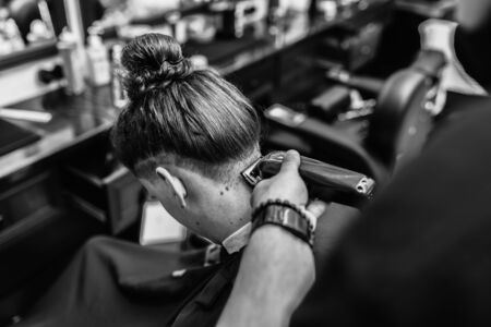 Barber makes a haircut and hair styling in a barbershop, beauty salon.の写真素材