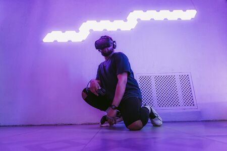 Man in a virtual reality helmet. Neon room with VR games.の写真素材