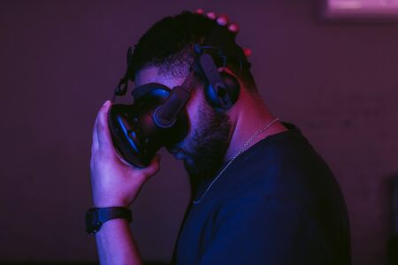 Man in a virtual reality helmet. Neon room with VR games. High quality photoの写真素材