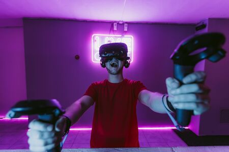 VR E-Sports. The guy is playing an online shooter in the game neon room.の写真素材