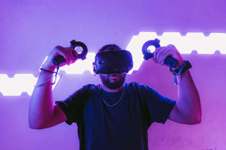 Virtual reality in a neon purple room. Man in VR glasses.の写真素材