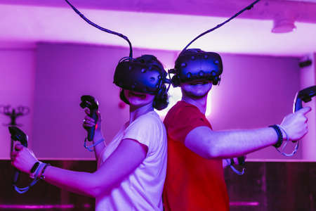 The guy and the girl play virtual reality games. Neon game room.の写真素材