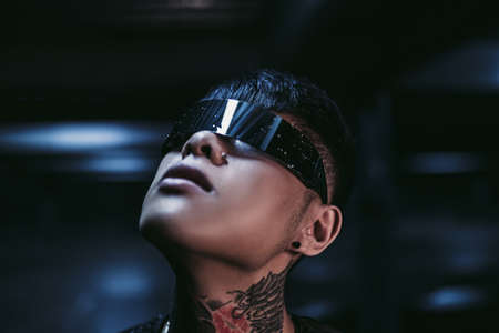 Cyberpunk. A man in futuristic glasses looks at the night sky. Night neon city.の写真素材