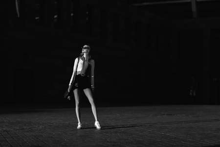 Contrasting black and white portrait of a woman with a skate in his hands.