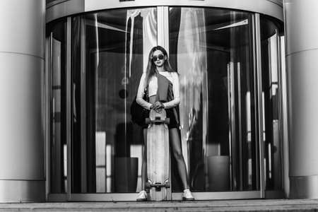 Lifestyle portrait of young woman with longboard.の写真素材