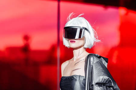 Stylish futuristic blonde in cyberpunk style on a red mirror background.の写真素材