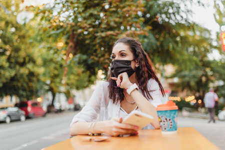 A young woman in a mask from the virus went for coffee. The city is in quarantine.の写真素材