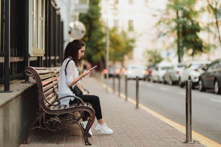 Young beautiful woman waiting for the bus at the stop.の写真素材