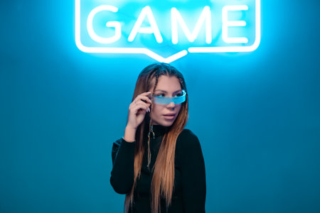 Young woman in cyber glasses in a neon room. Connecting to the game.の写真素材