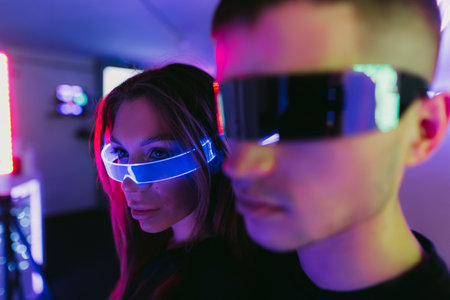 A couple of people standing under a neon light. Futuristic glasses.の写真素材