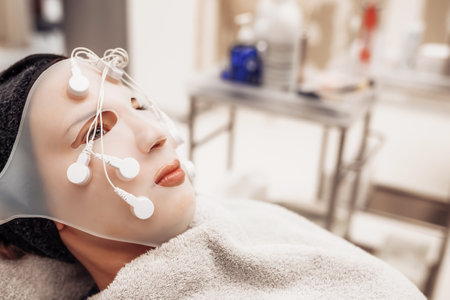 Woman receiving facial massage in beauty salon.
