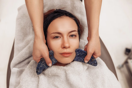 Woman receiving facial massage in beauty salon.の写真素材