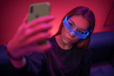 Woman with smartphone and neon glasses. Digitizationの写真素材