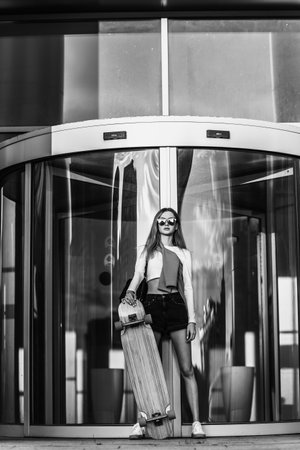 Woman on a skateboard in the city. Beautiful contrasting black and white photo of a woman riding around the city.の写真素材