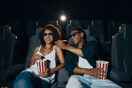 Couple watching comedy in 3d glasses with popcorn.の写真素材
