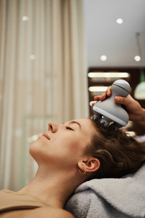 The master massages the womans head using a gadget.